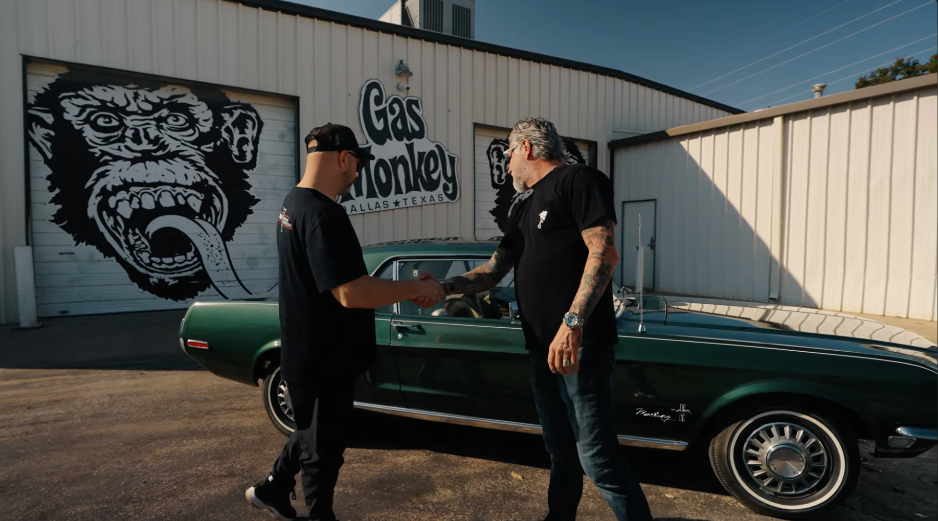 Two men shaking hands in front of a green car with 'Gas Monkey' branding.