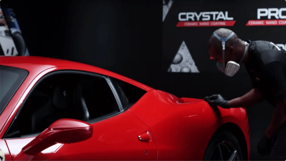 Person working on a red car with 'Crystal+' branding in the background